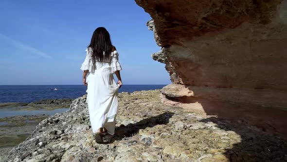 woman in white dress walking on cliffs