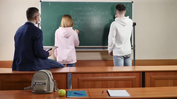 Teacher and Students Wearing Protective Masks Near the Blackboard During Quarantine