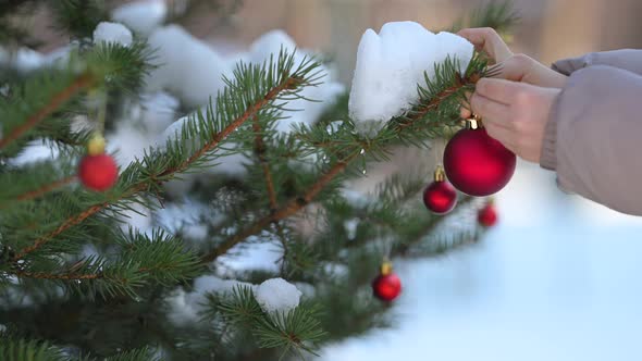 Children's hands in mittens decorate the Christmas tree