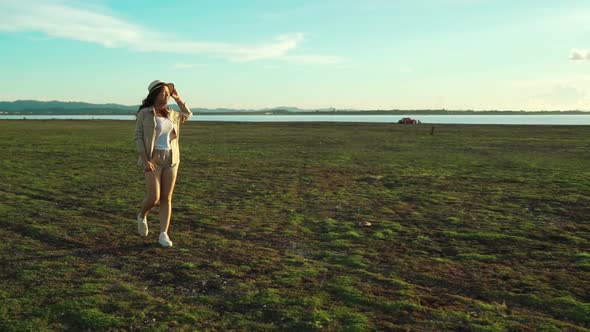slow-motion of cheerful woman walking across the green field with sunlight
