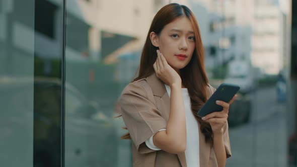 Asian Businesswoman using a mobile phone, working with a smartphone and looking at camera