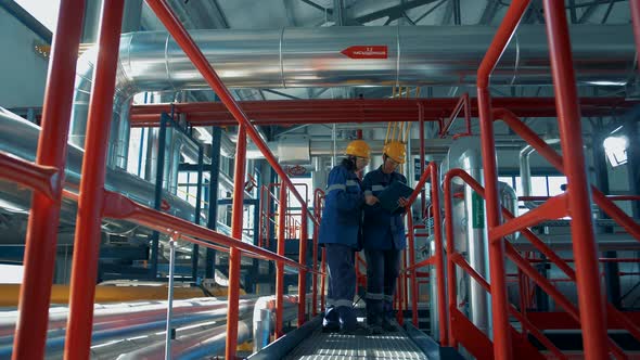 Oil refinery workers monitor the operation of the oil pipelines technological network alt