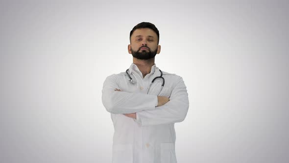 Young Male Caucasian Doctor Standing with Folded Hands on Gradient Background. alt