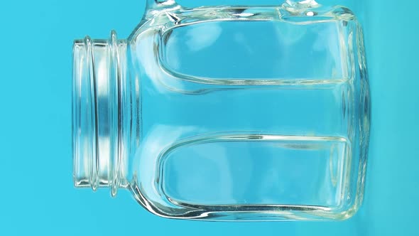 Vertical Video Closeup Shot of Milk Cold Beverage Drink Pooring Into Glass Jar Mug Blue Background