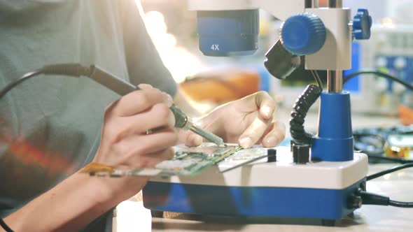 Engineer Is Soldering a Microcircuit Under a Microscope alt