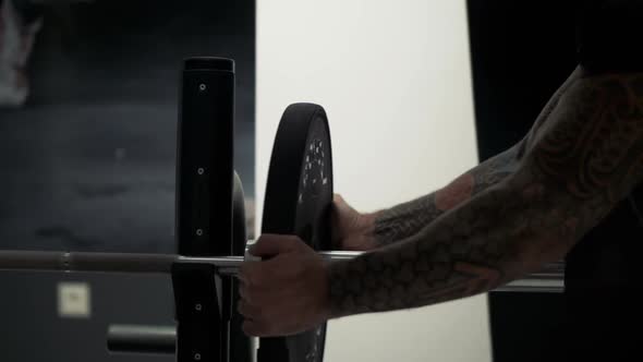 Man Puts Heavy Plates on Barbell