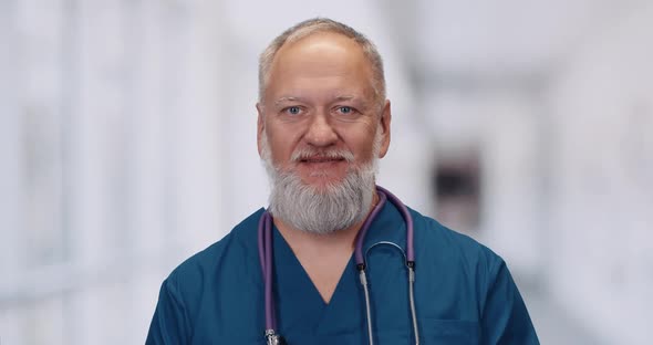 Portrait of a Doctor, Adult Gray-haired Man Looks at the Camera, Blurry Background. alt