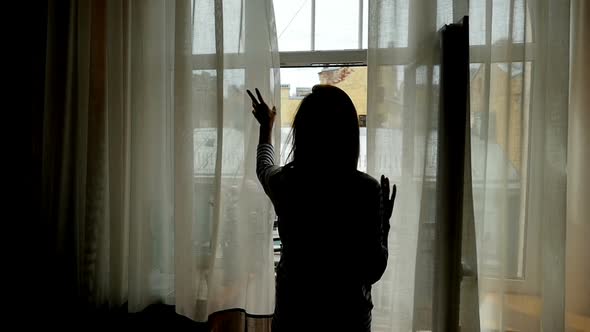 Rear View, Silhouette,  of Young Woman Opening Curtains on Window at Morning and Go Out to Balcony