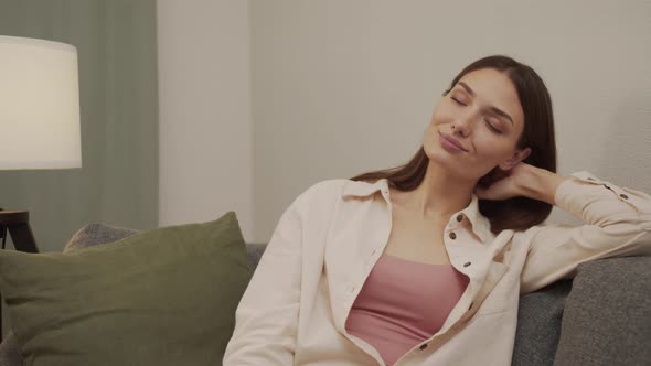 Tired Girl Takes Off Her Glasses Puts Them on the Table and Leans on the Sofa alt