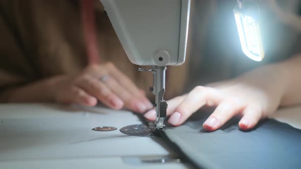 Stitching on sewing machine. Tailor sews on sewing machine. Close-up of woman's hand alt