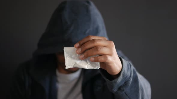 Drug Addiction Concept with Hand Holding Heroine Packet on Black Backgrund alt