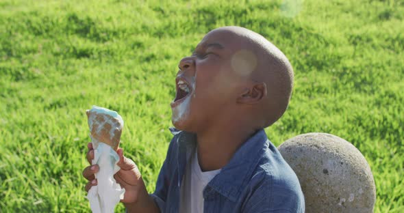 Video of happy african american boy eating ice creams and laughing on sunny day alt