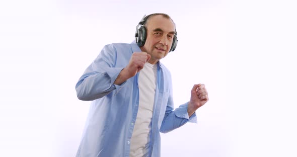 Slow Motion of Happy Enderly Man in Wireless Headphones Dancing Enjoying Music. Modern Devices alt