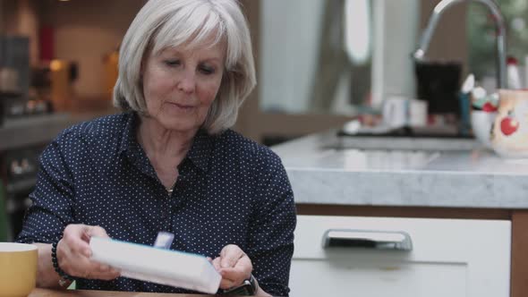 Senior Adult woman taking medicine at home in kitchen