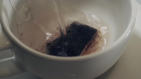 boiling water is poured into a mug with a tea bag. Brewing tea bags.