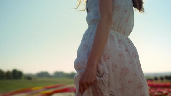 Unrecognizable Woman with Camera Looking Back at Garden with Spring Flowers alt