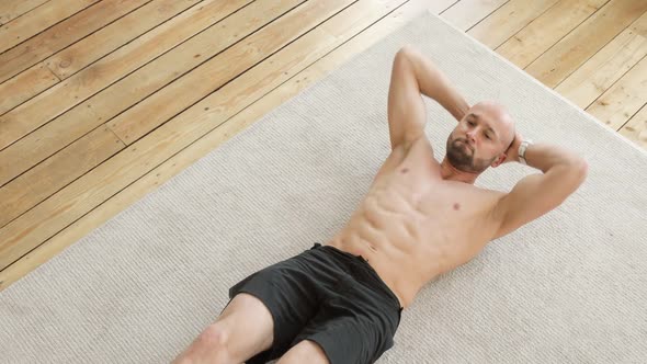 Athletic Muscular Man Doing Abs Exercises Crunches at Home on Floor, Top View