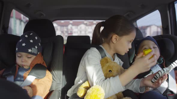 Girl Entertaining Fussy Brother during Car Ride alt