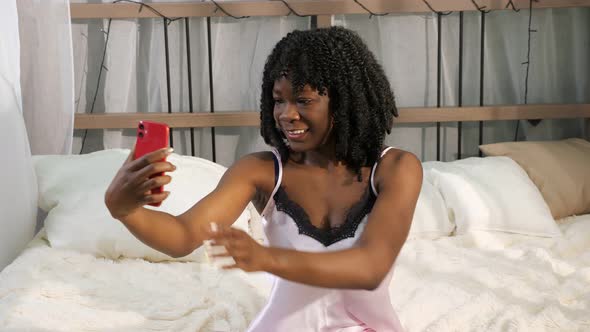 Lady Makes Selfie Fixing Curly Hair and Holding Smartphone alt