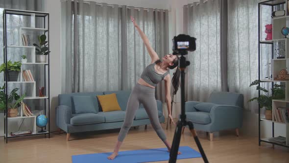Asian Trainer Female In Sports Clothes Speaking To Camera And Stretching While Teaching Exercise alt