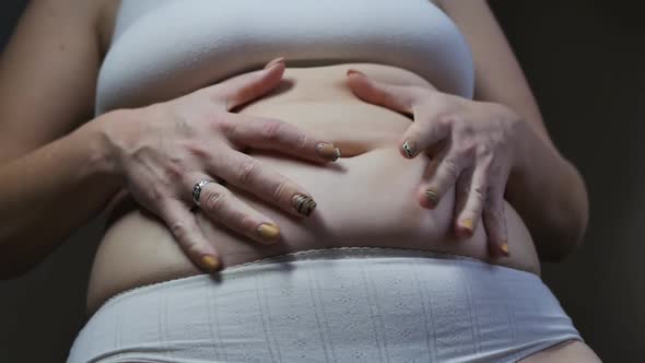 European Woman Squeezes Excess Belly Fat with Her Hands and is Indignant alt