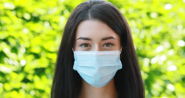 young woman with anti-covid mask turns left and smiles