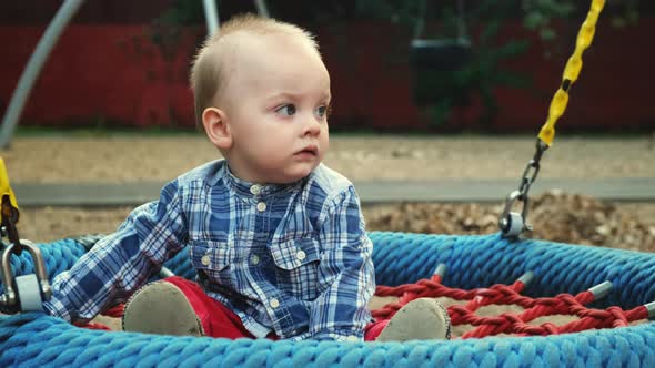 Bored One Year Old Toddler Swings on a Swing alt