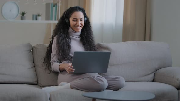 Joyful Successful Hispanic Girl Sit on Sofa Make Video Call Communicate Remote in Online Conference alt