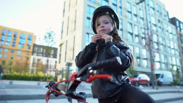 Little Girl Fixing Safety Helmet and Riding Bicycle on Street, Sport and Hobby