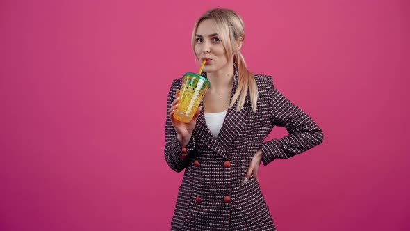 The Cheerful Young Woman with a Fresh Glass in Her Hand Smiles Drinks a Little of It and Finally alt