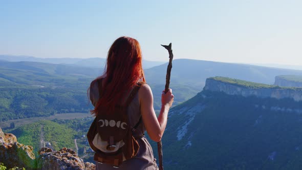 Girl with Backpack Staff Walks in Mountains alt