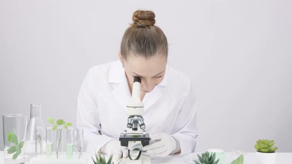 Female Biochemical Researcher Looking Through Microscope GMO Plant Green Leaf