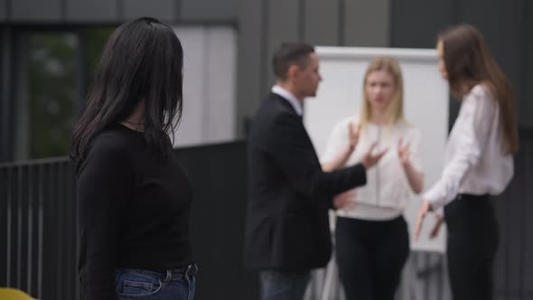 Caucasian Woman Closing Ears with Hands Looking at Camera As Nervous Colleagues Arguing at alt
