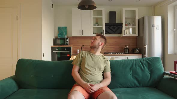 Guy Sits in the Living Room Looks Around at the Pop Up Thoughts with Commitments