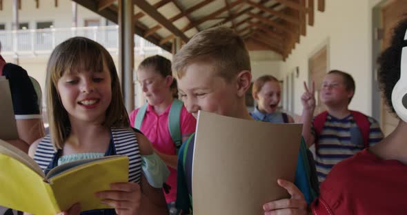 Group of kids with books walking in the school corridor alt