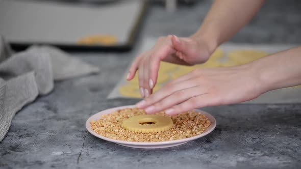 Woman Makes Round Peanut Cookies Sprinkled with Chopped Peanuts
