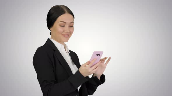 Smiling Businesswoman Checking Photos on Her Phone on Gradient Background alt