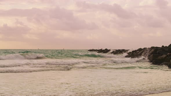 Waves crashing into a rocky pier alt