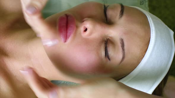 Massage Therapist Cosmetologist Makes Cheeks Massage for Woman in Beauty Salon alt