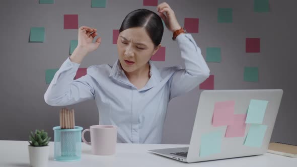 Asian woman feel confused working on a laptop and scratching her head