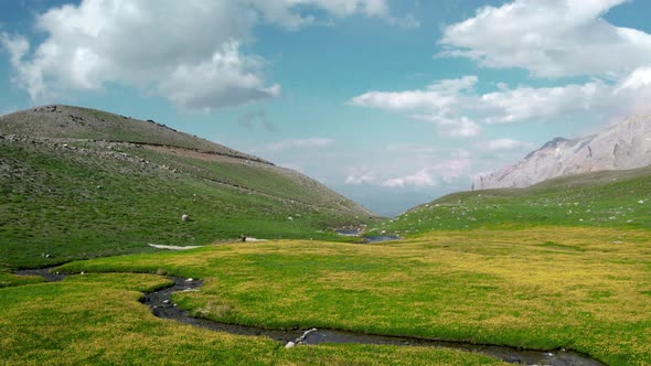 Green plateau among snowy mountains