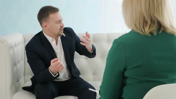 Businessman Sitting on Couch Talking to Female Psychologist alt