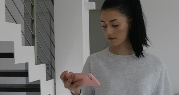 young woman in her house watching something on her smartphone