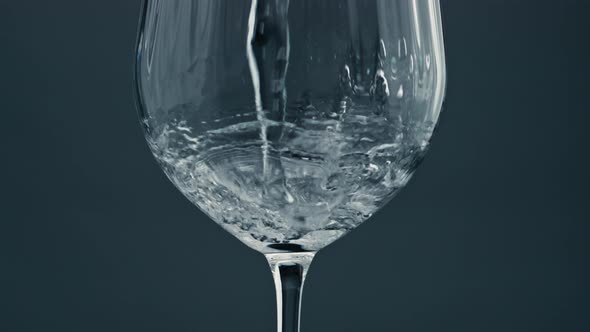Sparkling Water Pouring Glass at Dark Background Closeup alt
