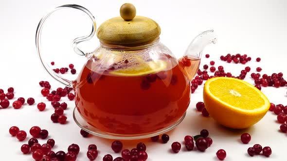 Fruit tea with cranberries and orange is in a glass teapot.