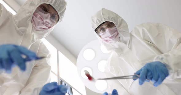 Surgeons in Protective Suits and Goggles Performing Surgery on Infectious Patient Bottom View Movie alt