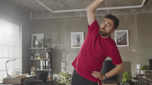 Young Athletic Man is Getting Ready to Daily Training at Home Warms Up and Stretches His Body in alt