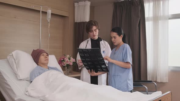 Female doctor explains x-ray film to patient at inpatient room bed in hospital. alt