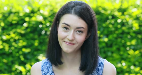 face portrait of young woman in a garden expressing mixed positive and negative emotions