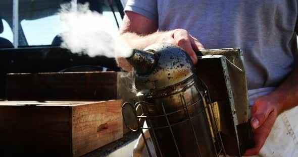Beekeeper preparing bee smoker on truck alt